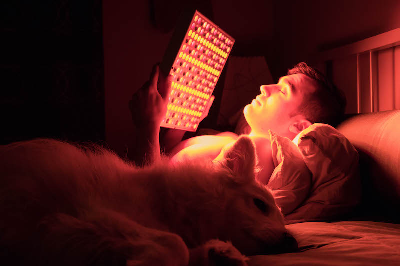 Man with a dog using a TrueDark Energy Square Orange Light Therapy