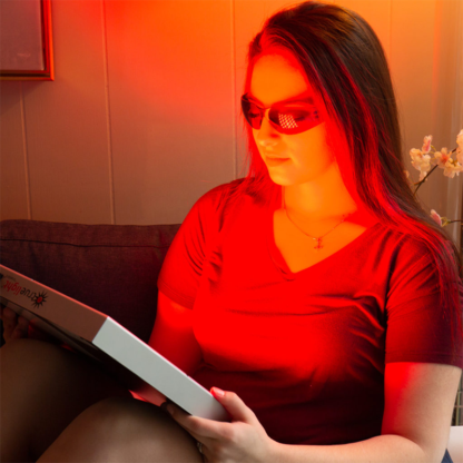 Woman wearing Calm Eye Shields while using TrueLight Energy Square Red Light Therapy