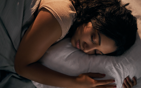 Young lady with dark hair hugging pillow while sleeping