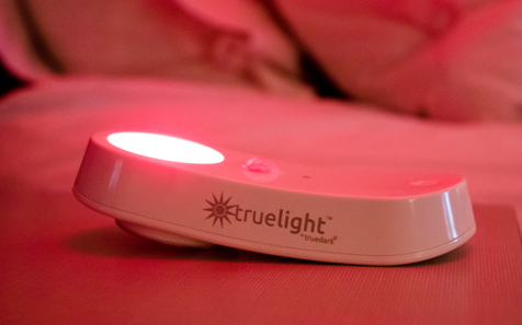 TrueLight Nightlight + Flashlight on bed illuminating red light