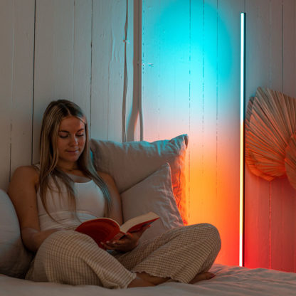 Woman reading a book next to the TrueLight Luna Red­™ Luminaire light stand in daylight mode