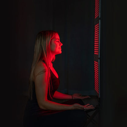 Young woman using the TrueLight Luna Red™ Trism with stand for red light therapy