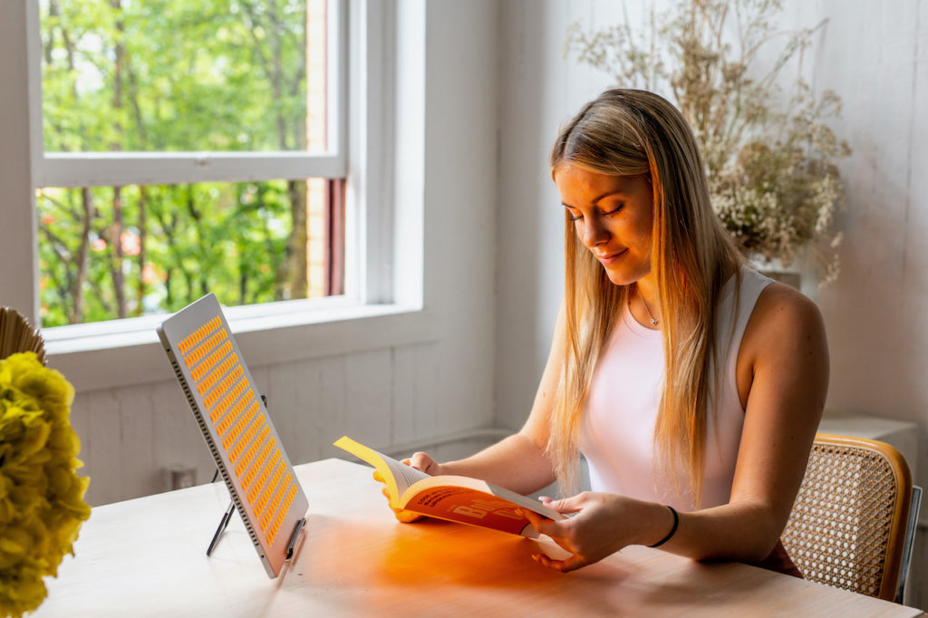 Image of woman using a TrueLight® Energy Square while reading a book